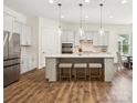 Bright kitchen featuring a large island with barstool seating and modern pendant lighting at 212 Portrait Way, Indian Trail, NC 28079