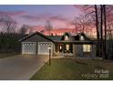 Charming home with a two-car garage, manicured lawn, and inviting front porch at twilight at 412 Wildlife Rd, Troutman, NC 28166