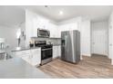 Modern kitchen featuring stainless steel appliances, white cabinets, gray counters and wood-look floors at 8024 Kennesaw Dr, Gastonia, NC 28056