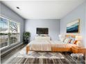 Virtually staged main bedroom with wood bed frame and large window at 8331 Burgundy Ridge Dr, Harrisburg, NC 28075
