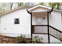 View of the white siding on the back of the home, a private porch, and wooded backyard at 1035 Timberlane Dr, Lincolnton, NC 28092