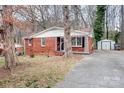 Inviting brick home with covered porch, storage shed, and paved driveway at 1418 Nottingham Rd, Kannapolis, NC 28081