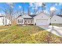 White house with brown accents, a two-car garage, and a grassy yard with fallen leaves at 242 Delview Dr, Cherryville, NC 28021