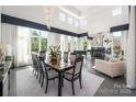 Bright dining area featuring a large chandelier, fireplace, piano, and large windows with natural light and a table set for ten at 15618 Frohock Pl, Charlotte, NC 28277