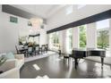 Bright and modern living room with piano, dining table and chairs, and large windows for natural light at 15618 Frohock Pl, Charlotte, NC 28277