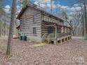 Rustic log cabin home with large wrap around porch and wooded surroundings at 2577 Dutch Rd, Mount Pleasant, NC 28124