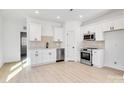 Modern white kitchen with stainless steel appliances and light wood floors at 1077 Gibson St, Albemarle, NC 28001