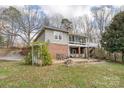 Brick home featuring a back patio seating area, garden beds, and lush greenery at 124 Muirfield Dr, Kings Mountain, NC 28086
