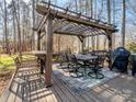 Outdoor dining area with pergola, table, chairs, and grill on a wooden deck at 4465 Red Hill Cir, Denver, NC 28037