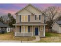 Two-story house with lights on, white porch and blue door at 3249 Ian Patrick Ave, Kannapolis, NC 28083