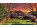 Spacious backyard featuring a lush green lawn, mature trees, and a cozy patio with a lovely sunset at 626 Lorain Nw Ave, Concord, NC 28027