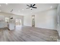 Spacious living room featuring light wood floors, a ceiling fan, and modern light fixtures at 122 Stockbridge Ln, Statesville, NC 28625