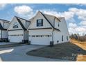Rear view of townhome showcasing white siding, two-car garage, and yard at 7025 Old Evergreen Pkwy, Indian Trail, NC 28079