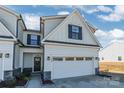 Front view of two-story townhome with white siding and a two-car garage at 7025 Old Evergreen Pkwy, Indian Trail, NC 28079