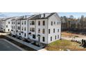 Three story townhouses with white siding, black roofing and landscaping at 15306 Ballancroft Pkwy # 21, Charlotte, NC 28277