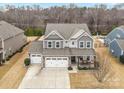 Aerial view showcases home's three-car garage, gray siding, manicured lawn, and mature trees in a desirable neighborhood at 3332 Delaware Dr, Denver, NC 28037