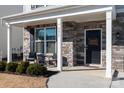 Covered porch with stone facade, two wicker chairs, and a welcoming sign at 4479 Dover Ct, Denver, NC 28037