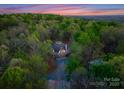 Stunning aerial view of unique home design nestled amongst trees, with a colorful sunset sky at 10200 Amsterdam Dr, Mount Pleasant, NC 28124