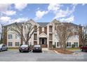 Exterior view of a three-story building with brick and beige siding and manicured landscaping at 10240 Rose Meadow Ln # D, Charlotte, NC 28277