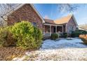 Brick house with a covered porch, partially covered in snow, and winter landscaping at 110 Robin Rd, Lincolnton, NC 28092