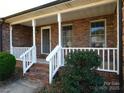 Close-up of the covered front porch featuring brick steps, white railings, and a welcoming entryway at 110 Robin Rd, Lincolnton, NC 28092