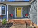 Inviting front porch with yellow door and brick steps at 1147 Bloom Wood Ln, Matthews, NC 28105