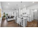 Open-concept kitchen with white cabinets, stainless steel appliances, island seating, and hardwood flooring at 3113 Beacon Heights Rd, Indian Land, SC 29707