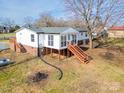 Back exterior view of this beautiful home, featuring an enclosed sunroom and spacious yard at 3416 Polkville Rd, Shelby, NC 28150