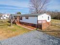 Wide shot of a single-story home with brick foundation, wooden decks and gravel driveway at 3416 Polkville Rd, Shelby, NC 28150