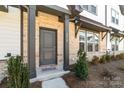 Townhome entrance with a gray door, brick facade, and well-maintained landscaping at 8928 Morning Mist Rd, Charlotte, NC 28215