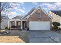 Brick ranch home with attached garage and landscaped lawn at 10318 Threatt Woods Dr, Charlotte, NC 28277