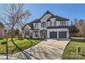 Two-story house with white brick exterior, gray garage doors, and manicured lawn at 18038 Greyfield Gln, Fort Mill, SC 29707