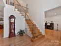 Grand staircase with wooden railing and a grandfather clock in the foyer at 8839 Blooming Arbor St, Huntersville, NC 28078