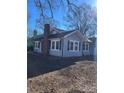 Side view of gray house with blue shutters, brick chimney, and landscaping at 924 E Main St, Albemarle, NC 28001