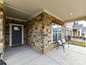 Stone and gray exterior, inviting front porch with a bench at 1115 Millview Ln, Matthews, NC 28104