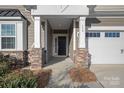 Front entrance with stone accents, columns, and a black door at 116 Van Gogh Trl, Mount Holly, NC 28120