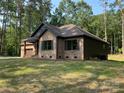 Angle of new construction home with low profile roof and tidy front lawn with mature trees and fresh sod at 305 General As Johnston St, Stanley, NC 28164