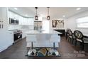 Modern kitchen with white cabinets, island, and stainless steel appliances at 1233 Rollingwood Dr, Charlotte, NC 28217