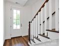 Bright foyer with hardwood floors, a staircase with wood and white balusters, and a glass door at 421 Delburg Mill Alley Dr, Davidson, NC 28036