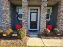 Front entry with stone pillars, red planters, and a dark-stained door at 5860 Clan Maclaine Dr, Charlotte, NC 28278