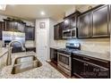 Close up of stainless appliances, granite countertops, a double sink and dark cabinets in the kitchen at 3033 Honeylocust Ln, Fort Mill, SC 29707