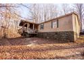 Single-wide mobile home with stone foundation and covered porch, nestled in a wooded setting at 338 Piney Grove Rd, Harmony, NC 28634