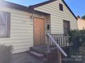 Front view of a yellow house with a boarded-up front door and steps leading to the entrance at 3101 Dogwood Ave # 3, Charlotte, NC 28206