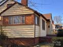 Side view of a yellow house with brown accents, showcasing its siding and brick foundation at 3101 Dogwood Ave # 3, Charlotte, NC 28206