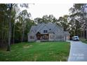 A home featuring stone, brick, and complementary gray toned siding, set against a backdrop of mature trees and green lawn at 6507 Rehobeth Rd # 4, Waxhaw, NC 28173