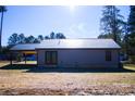 Rear view of home showcasing gray metal siding, black metal roof, and double doors at 411 E Gary St, Candor, NC 27229