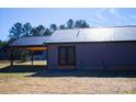 Rear view of home showcasing gray metal siding, black metal roof, and double doors at 411 E Gary St, Candor, NC 27229