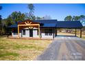Gray metal siding home with black metal roof, covered porch, and carport at 411 E Gary St, Candor, NC 27229