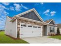 Side view of a house with stone and vinyl siding, and a two-car garage at 111 Adams Tree Way, Troutman, NC 28166
