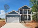 This new construction two-story home features a two-car garage, light blue siding, and a charming front porch with black railings at 8078 Blackwood Rd, Denver, NC 28037